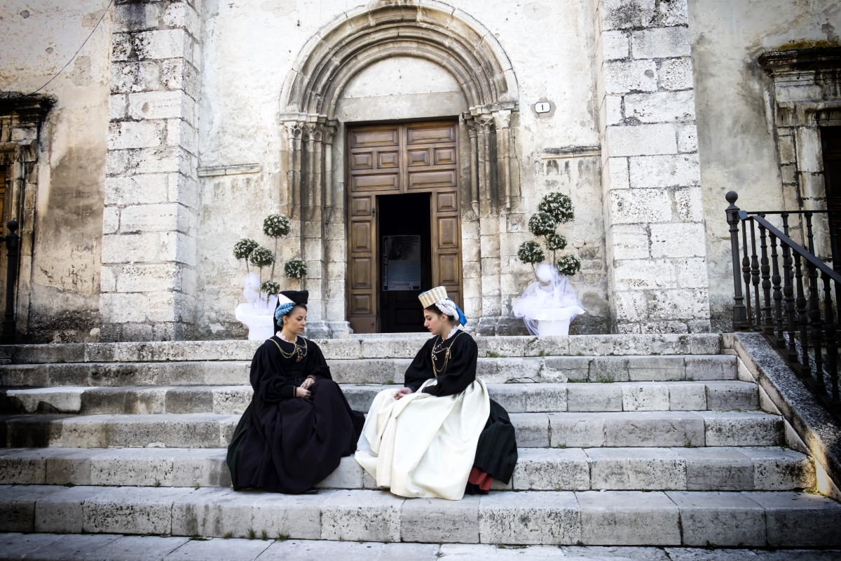 Due donne con indosso i costumi tradizionali di Scanno sulla gradinata della Chiesa di Santa Maria della Valle - ENIT SpA