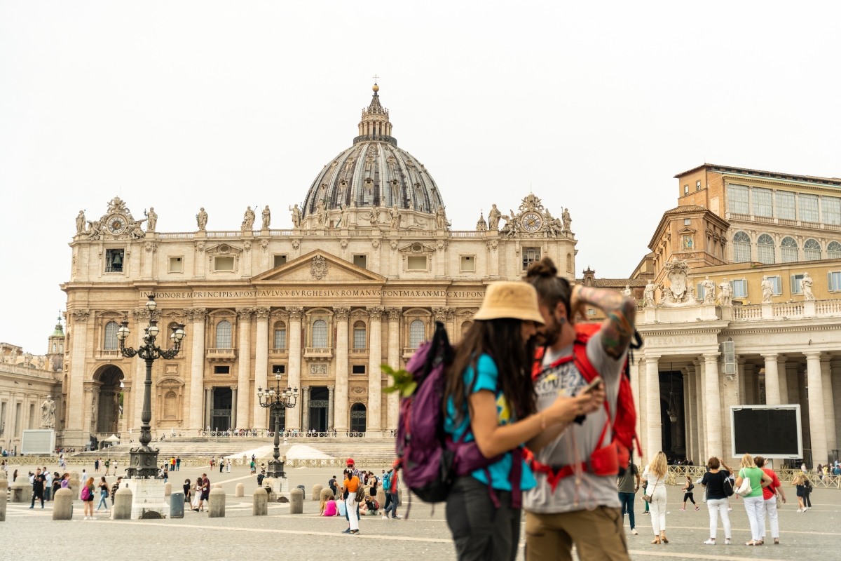 Two pilgrims on the Via Francigena standing in front of St Peter's Basilica - ENIT SpA