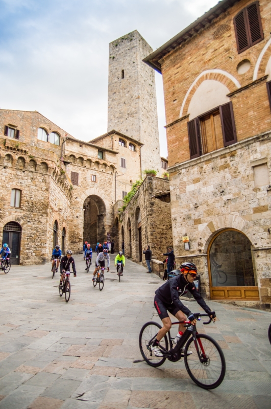 San Gimignano, ciclisti in piazza della Cisterna; sullo sfondo, la Torre dei Becci - ENIT SpA