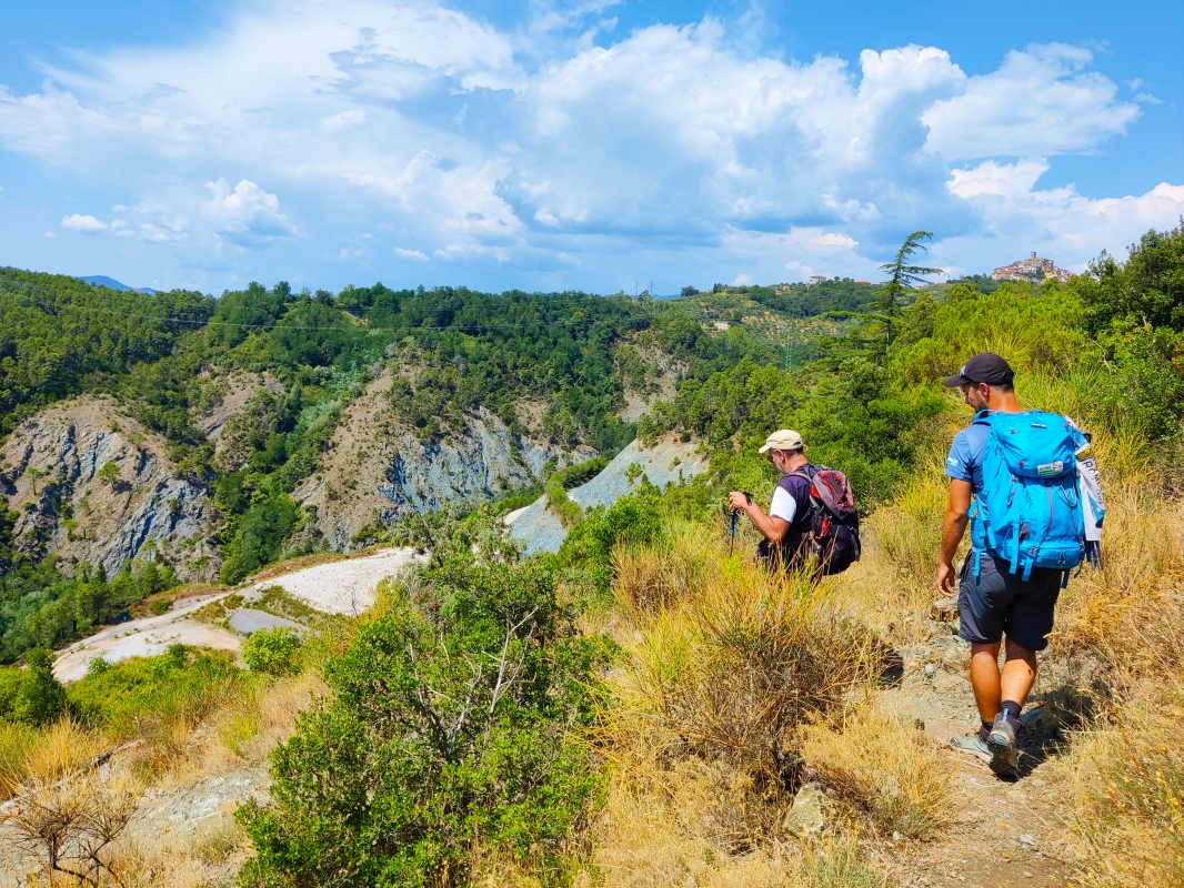 Two pilgrims on the Via Francigena, in the background on the right the village of Ponzano Superiore - ENIT SpA